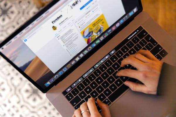 Hands typing on a laptop at a desk, engaging in online work, and navigating social media.